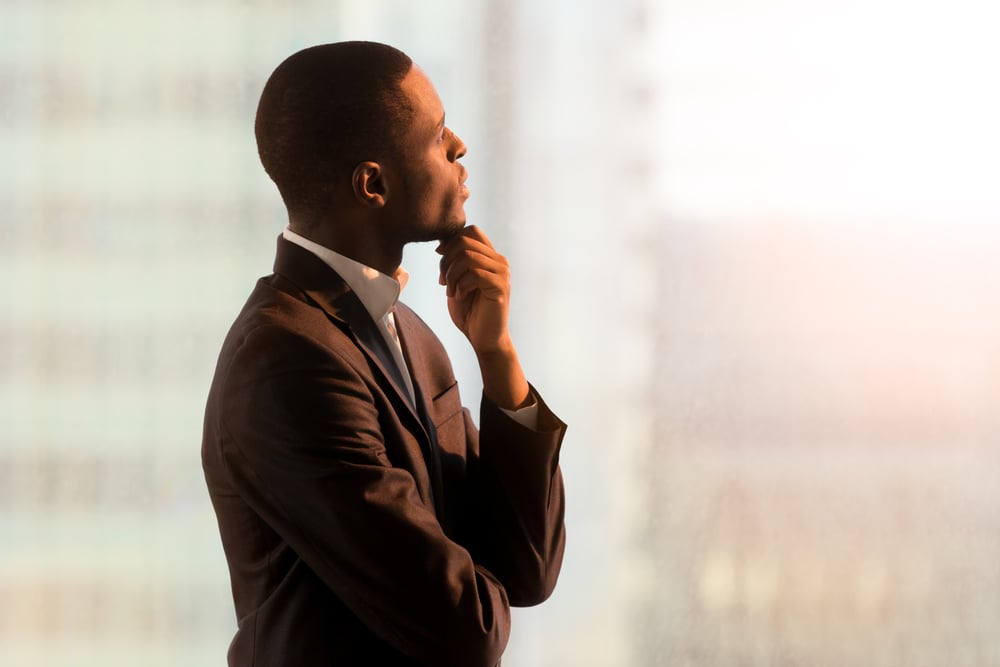 Portrait of pensive businessman standing near window and thinking about decision